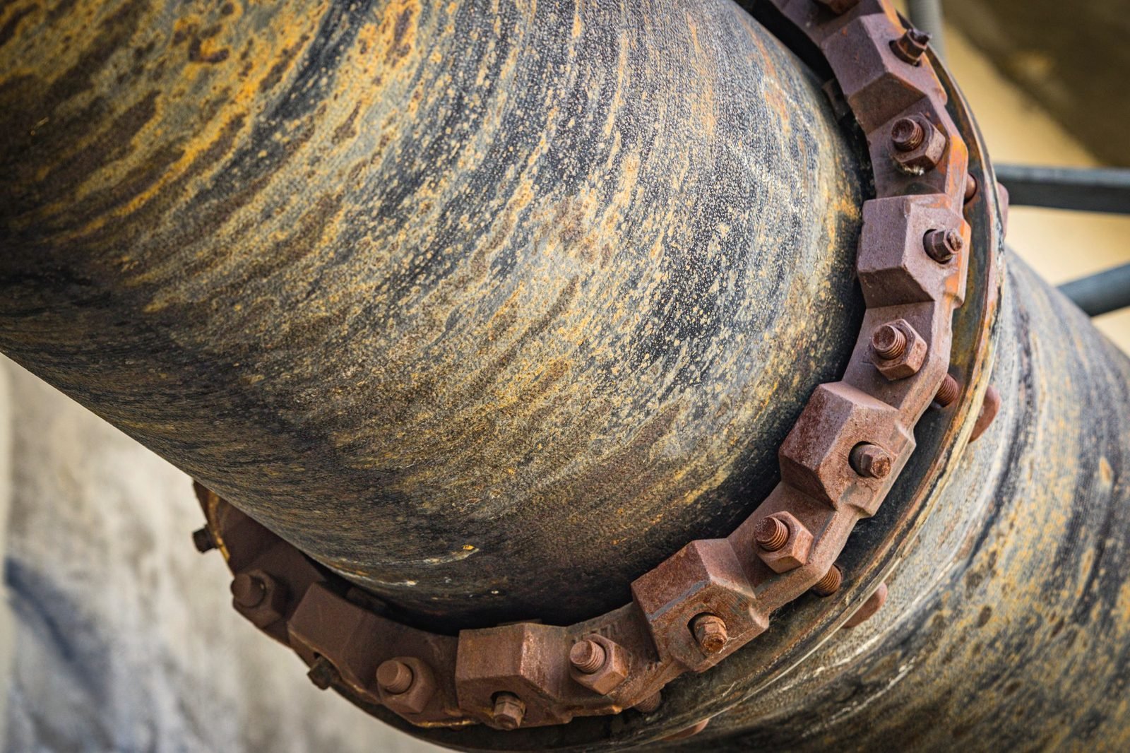 Close-up of a heavy roller chain wrapped around a scarred steel pipe