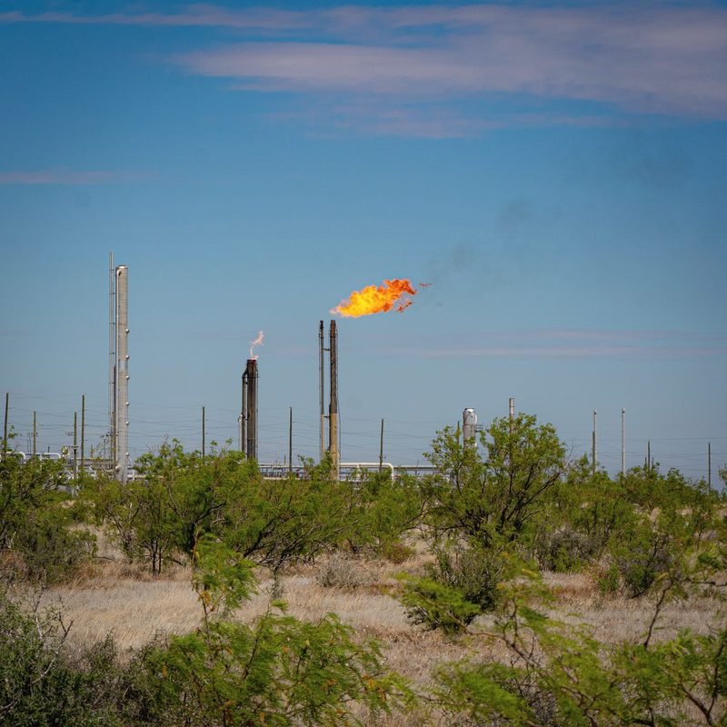 A gas flare burning above mesquite brush in the Permian Basin